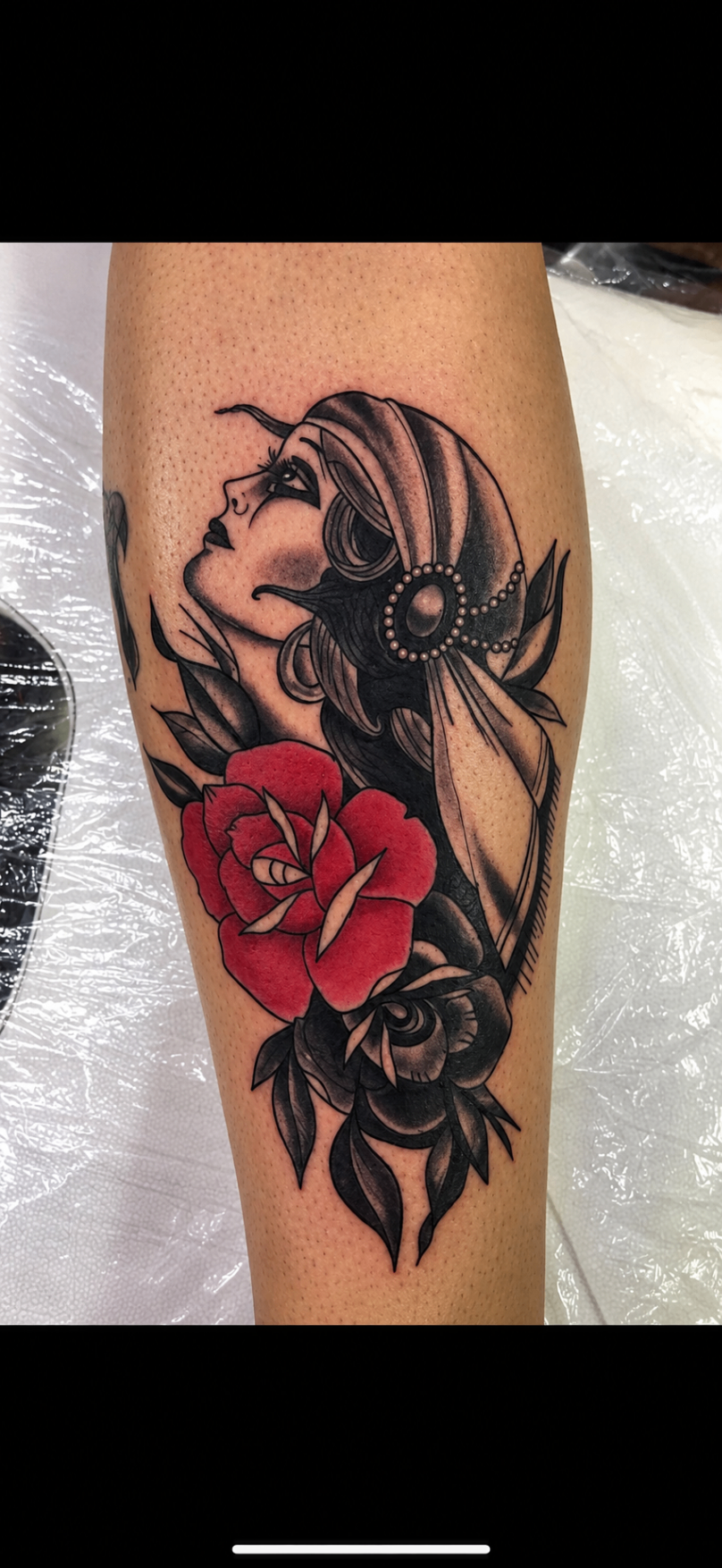 Tatouage néo-traditionnel d’une femme au foulard avec une rose rouge