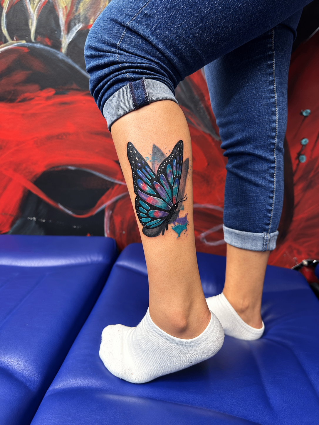 Tatouage néo-traditionnel d’un papillon coloré sur le mollet