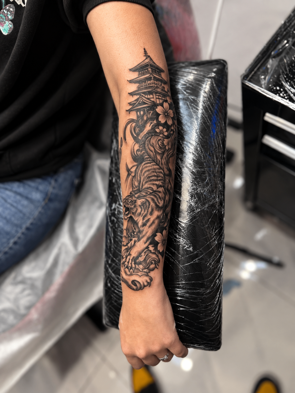 Tatouage néo-traditionnel d’un tigre et d’une pagode japonaise sur l’avant-bras