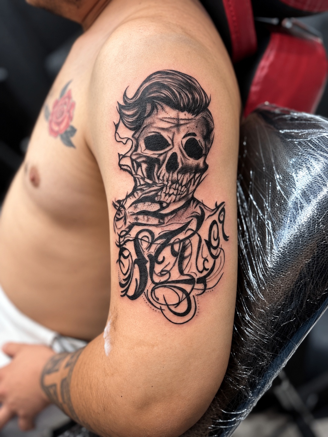 Tatouage Black & Grey de crâne et lettering sur le bras