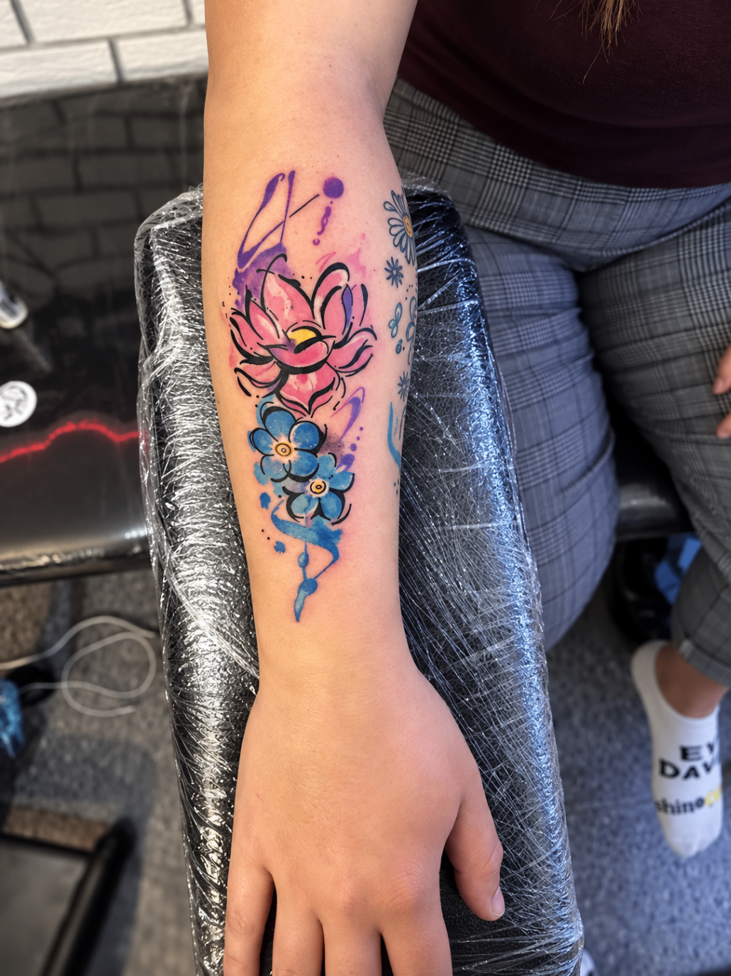 Tatouage néo-traditionnel d’un lotus et de fleurs bleues sur l’avant-bras