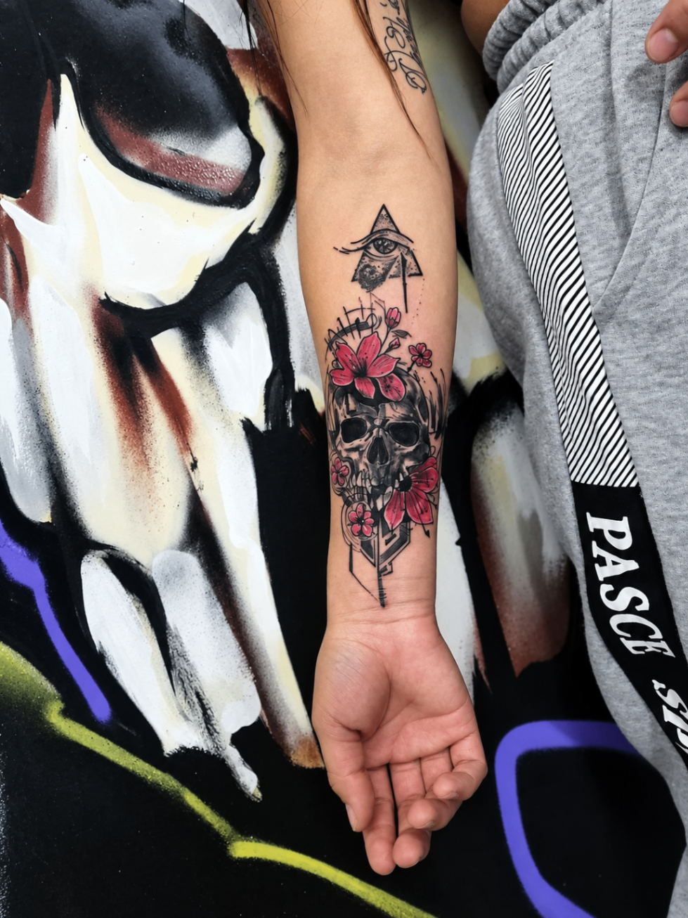 Tatouage néo-traditionnel d’un crâne fleuri et d’un œil dans un triangle