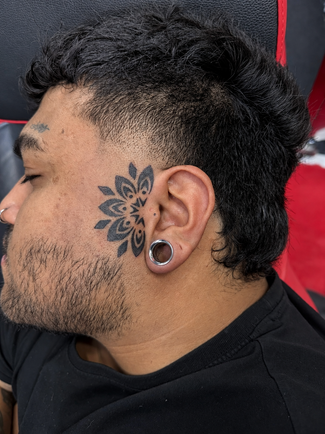 Tatouage Blackwork de mandala géométrique devant l’oreille