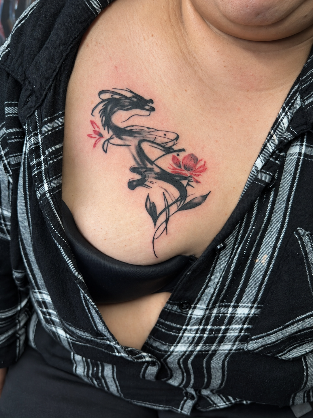 Tatouage Blackwork d’un dragon aux fleurs rouges sur la poitrine