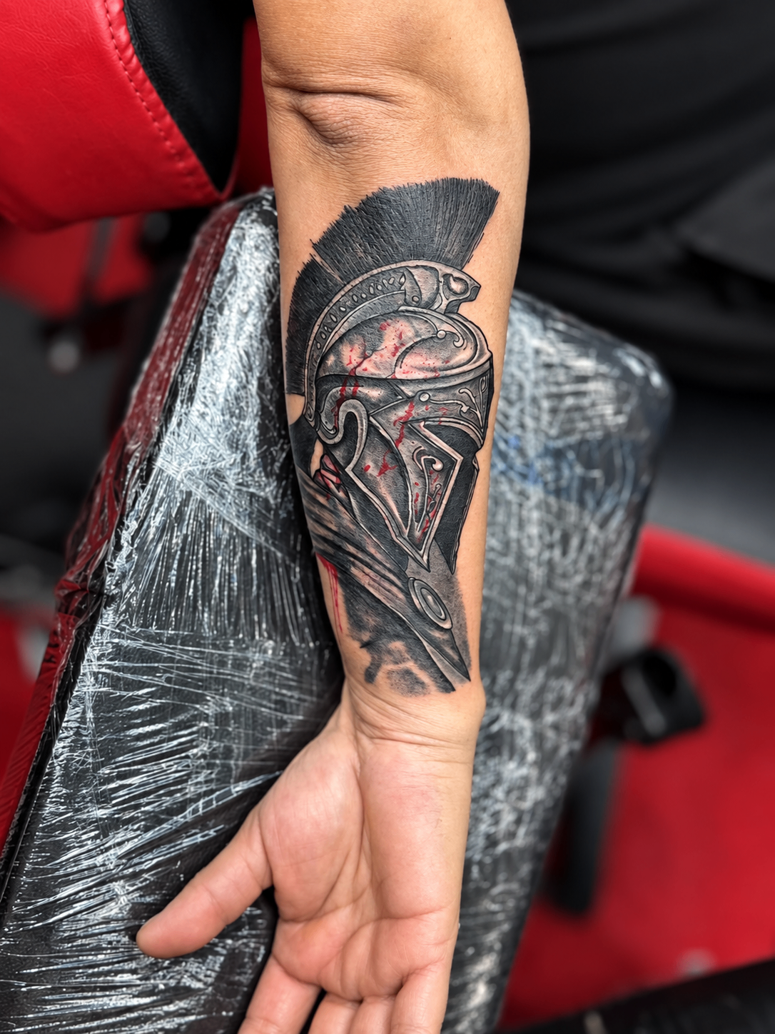Tatouage Black & Grey d’un casque spartiate sur l’avant-bras