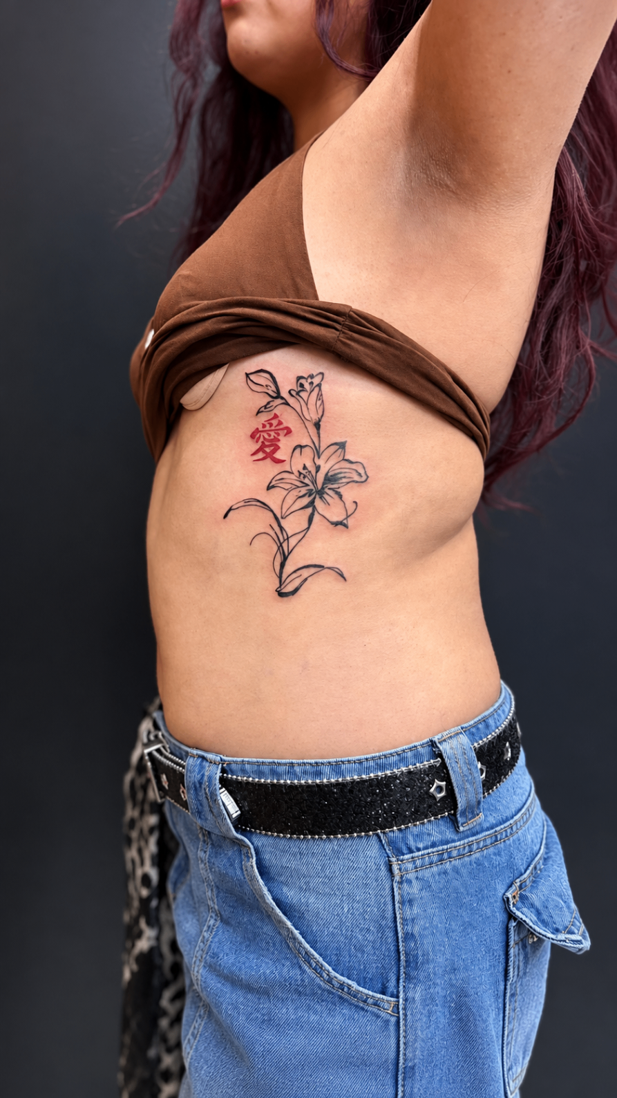 Tatouage Fine Line de lis avec le caractère amour en rouge sur les côtes